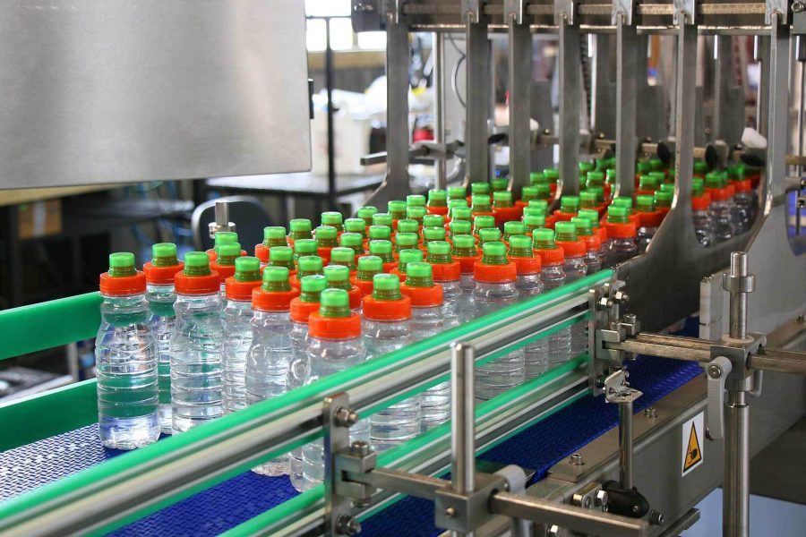 Empty bottles entering the shrink wrapper machine for packaging.